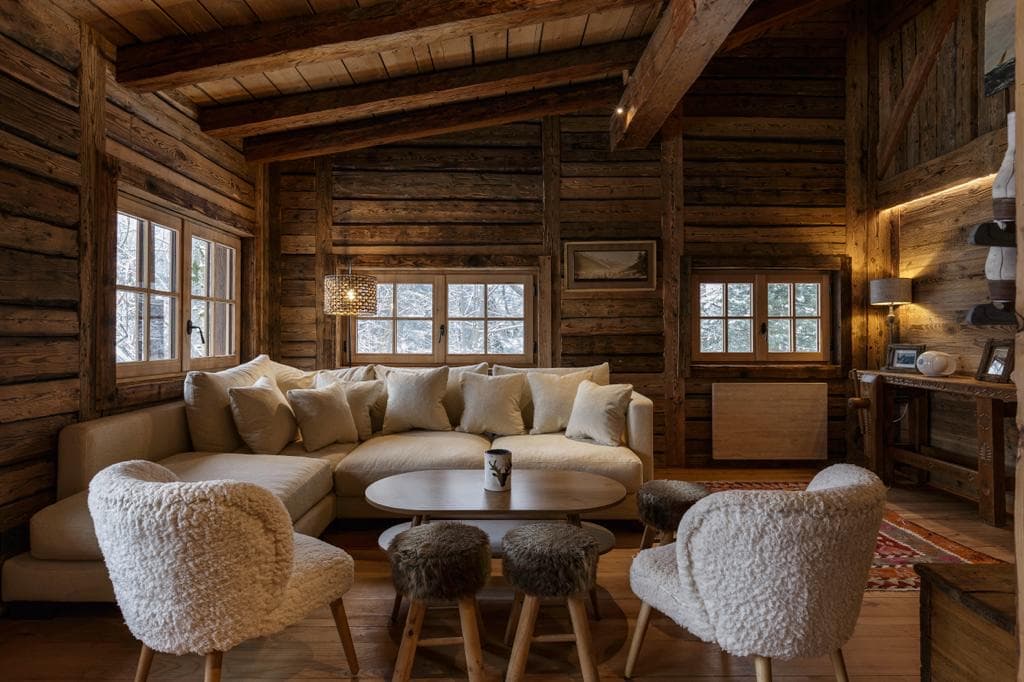 Salon du chalet Le Solerey avec fauteuils en peau de mouton et tabourets