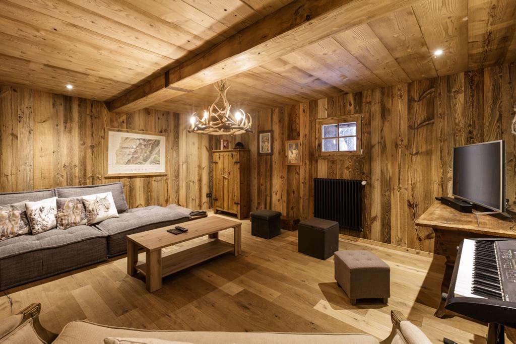 Salon télévision et piano du chalet Le Solerey, lustre en bois de cerf